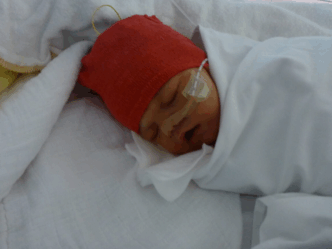 ziekenhuis met pasgeboren baby met rode muts met slang langs wang